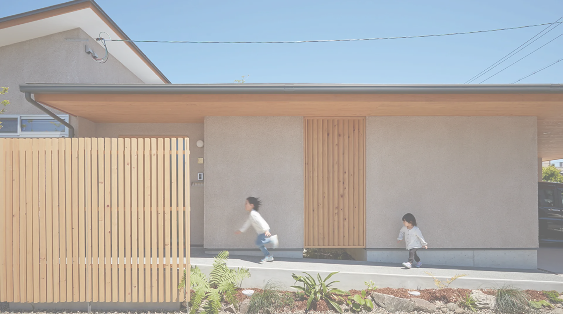 木製格子がある平屋の玄関前を走る子どもたち
