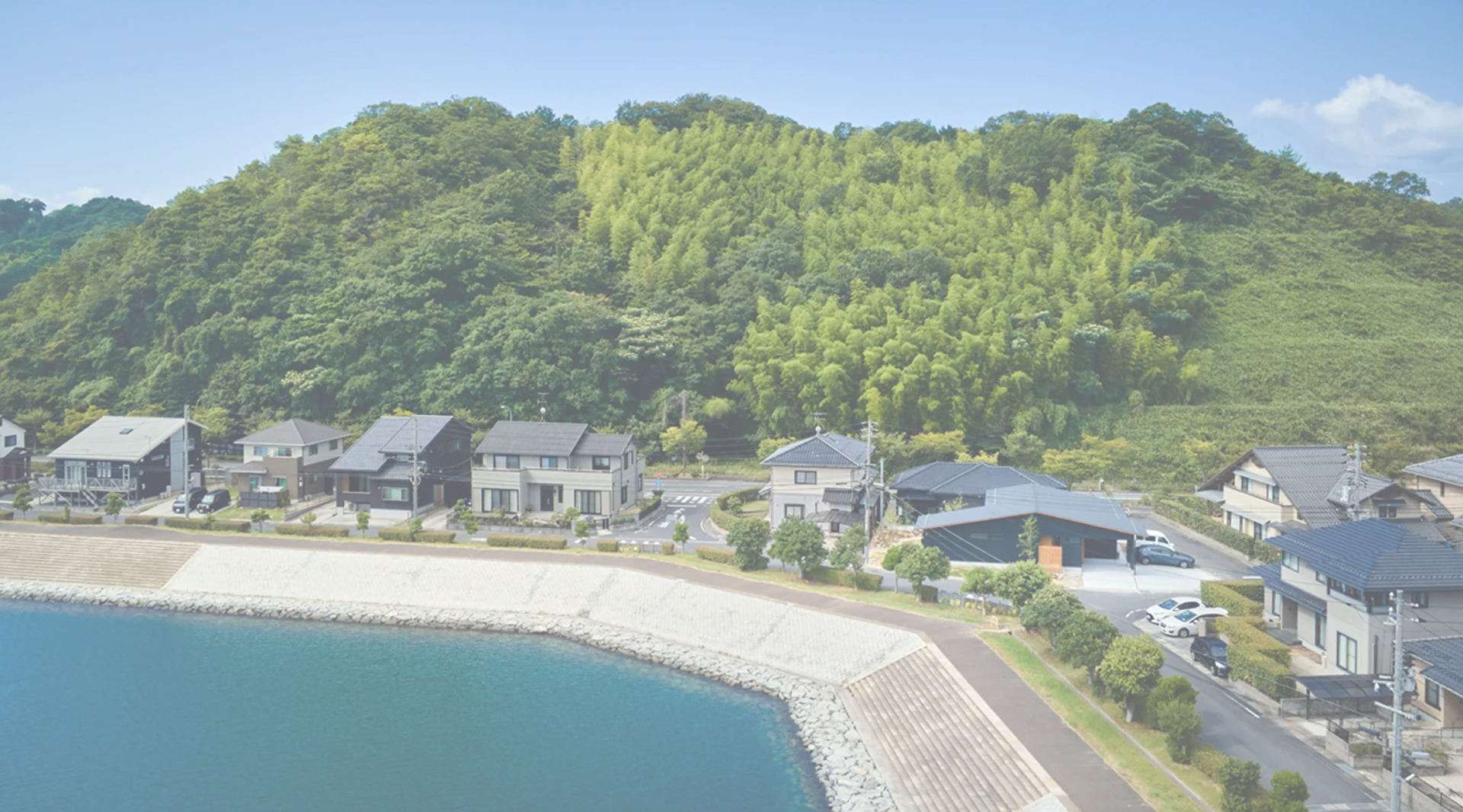 海沿いに建つ住宅街と背後の緑豊かな山並み
